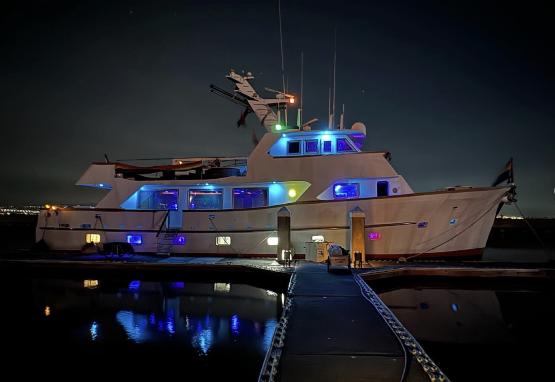 Yacht docked at night with colorful underwater and deck lights